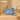 Blue handbag with decorative handle and strap on a beige surface, featuring the Wrangler brand.
